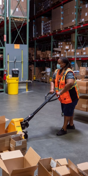 Woman with a pallet mover on the warehouse floor